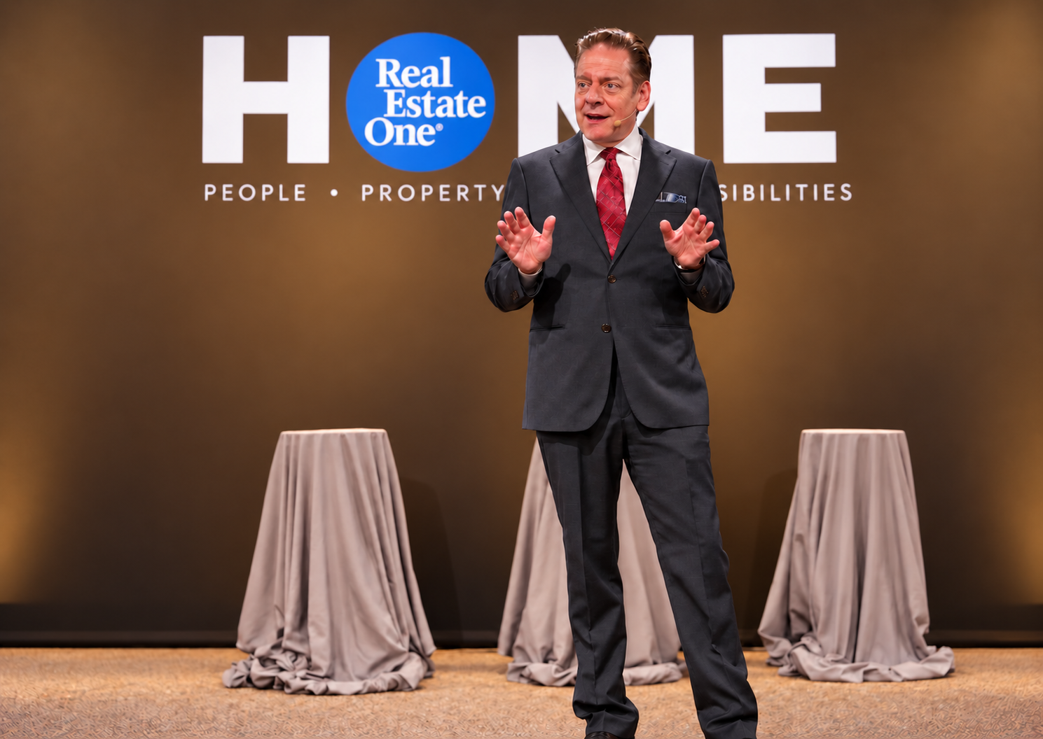 Mike Thornton in a gray suit and red tie performing at a corporate event